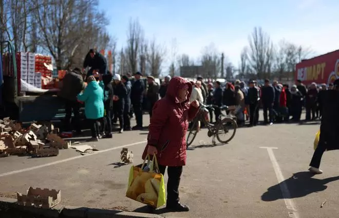 A woman carries a bag with food as volunteers deliver it to people from the donations of other countries, as Russia’s invasion of Ukraine continues, in Mykolaiv, Ukraine, March 28, 2022. 