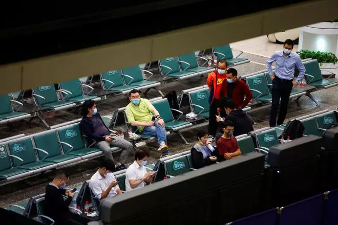 People sit in an area where relatives of the passengers of the China Eastern Airlines Boeing 737-800 plane, which crashed in Wuzhou flying from Kunming to Guangzhou, wait for news, at Guangzhou Baiyun International Airport in Guangzhou, Guangdong province, China March 22, 2022. 